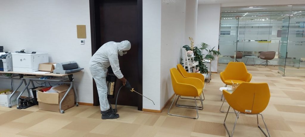 Pest control technician applying treatment at an indoor doorway in Dubai